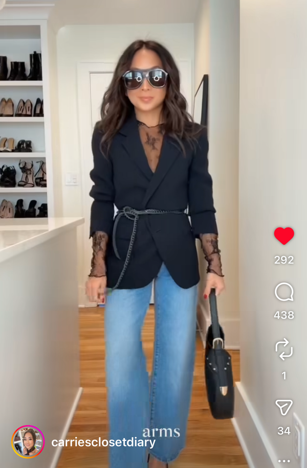 Woman wearing a black blazer, blue jeans, sunglasses, and a thin leather tie belt with studs in a closet 
