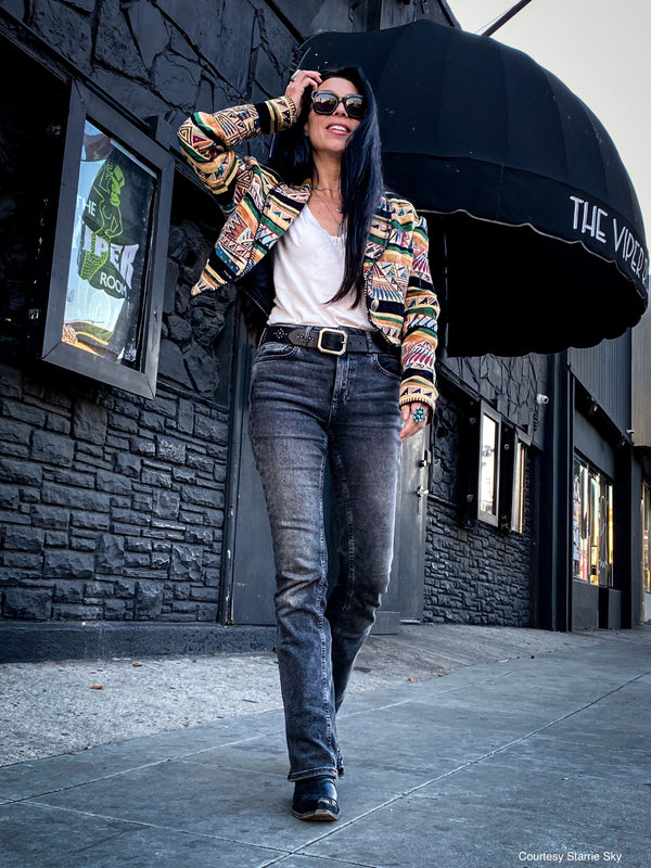 Woman walking in front of the Viper Room building wearing a colorful jacket, black jeans, and a black studded leather belt